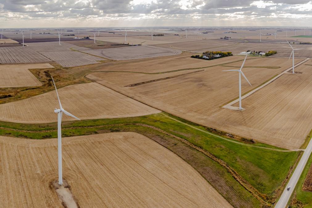 An aerial view of wind turbines scattered across farm fields in Howard County, Iowa.